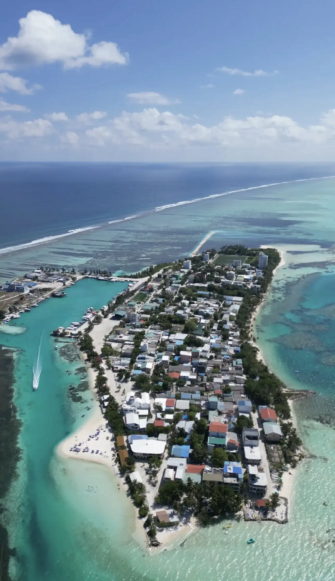 Aerial view of a local island with its harbour and reef in the atoll