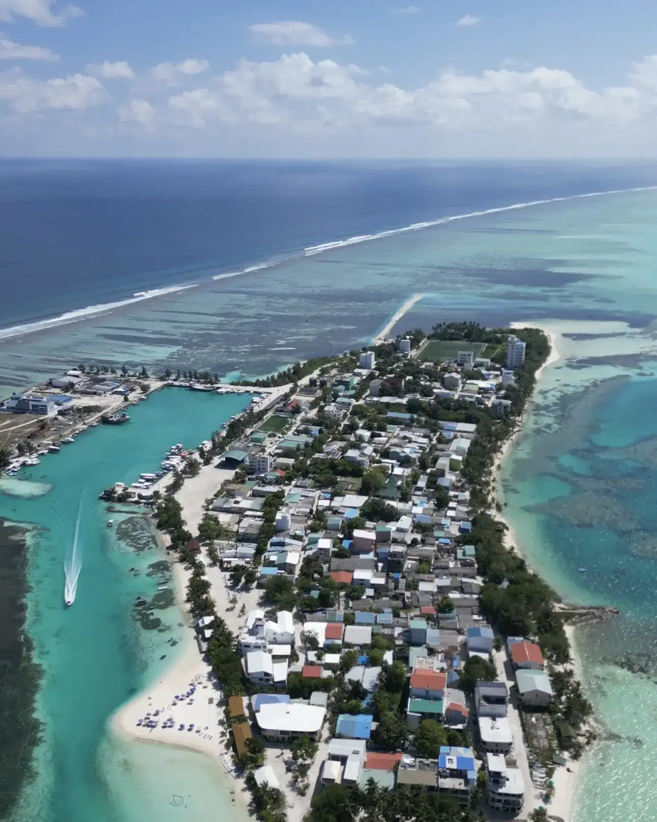 Aerial view of a local island with its harbour and reef in the atoll
