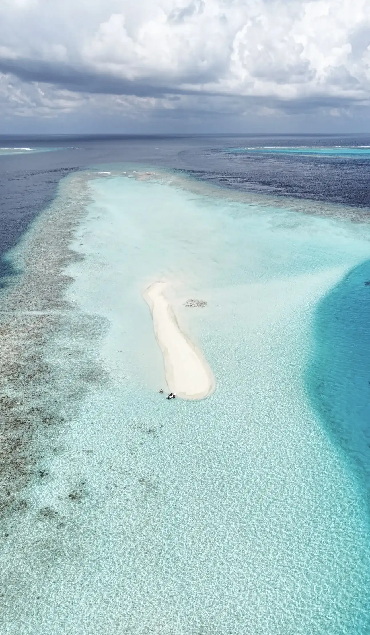 Aerial view of a narrow sandbank surrounded by reef and shallow lagoon