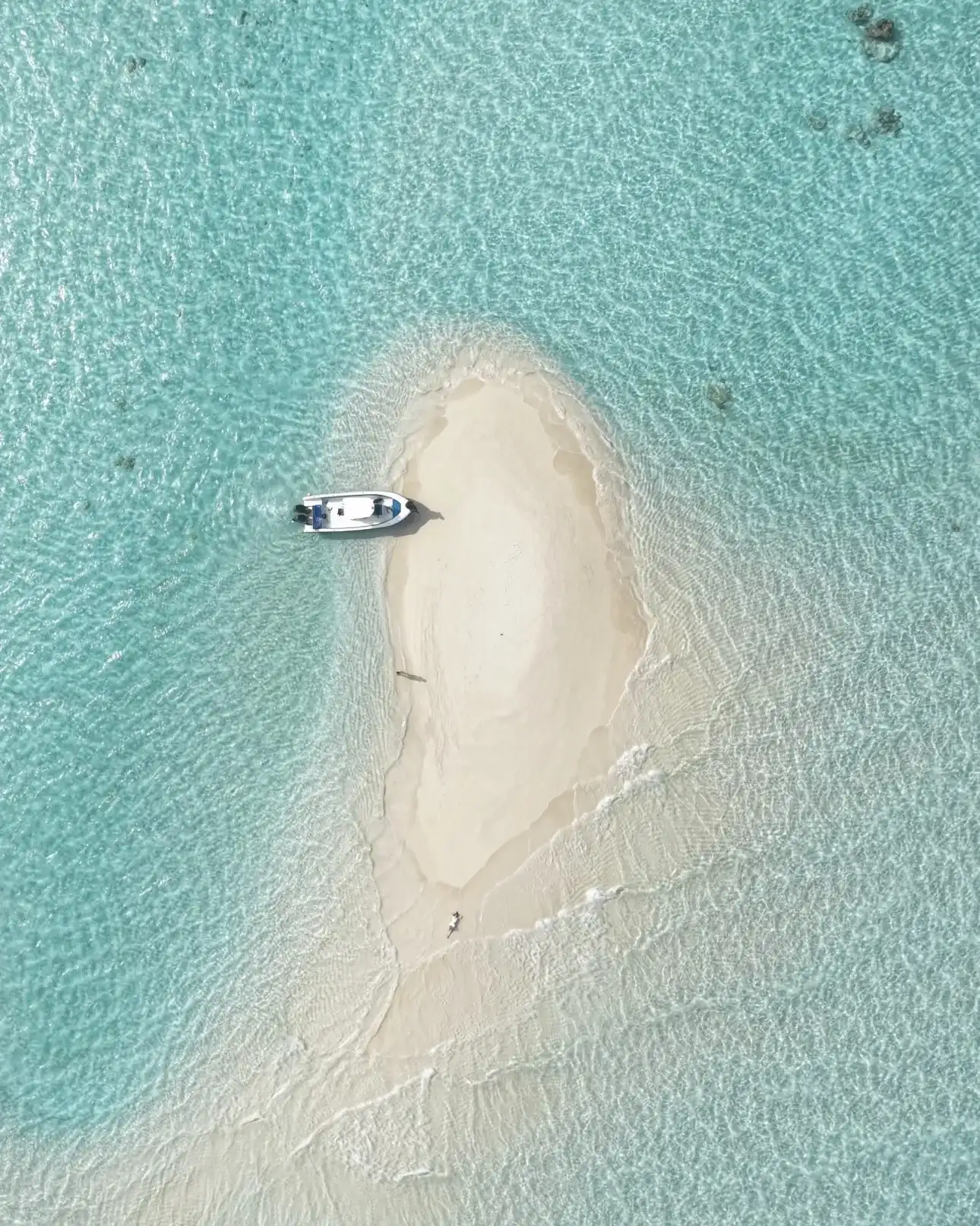 Aerial view of a small round sandbank with a boat moored beside it