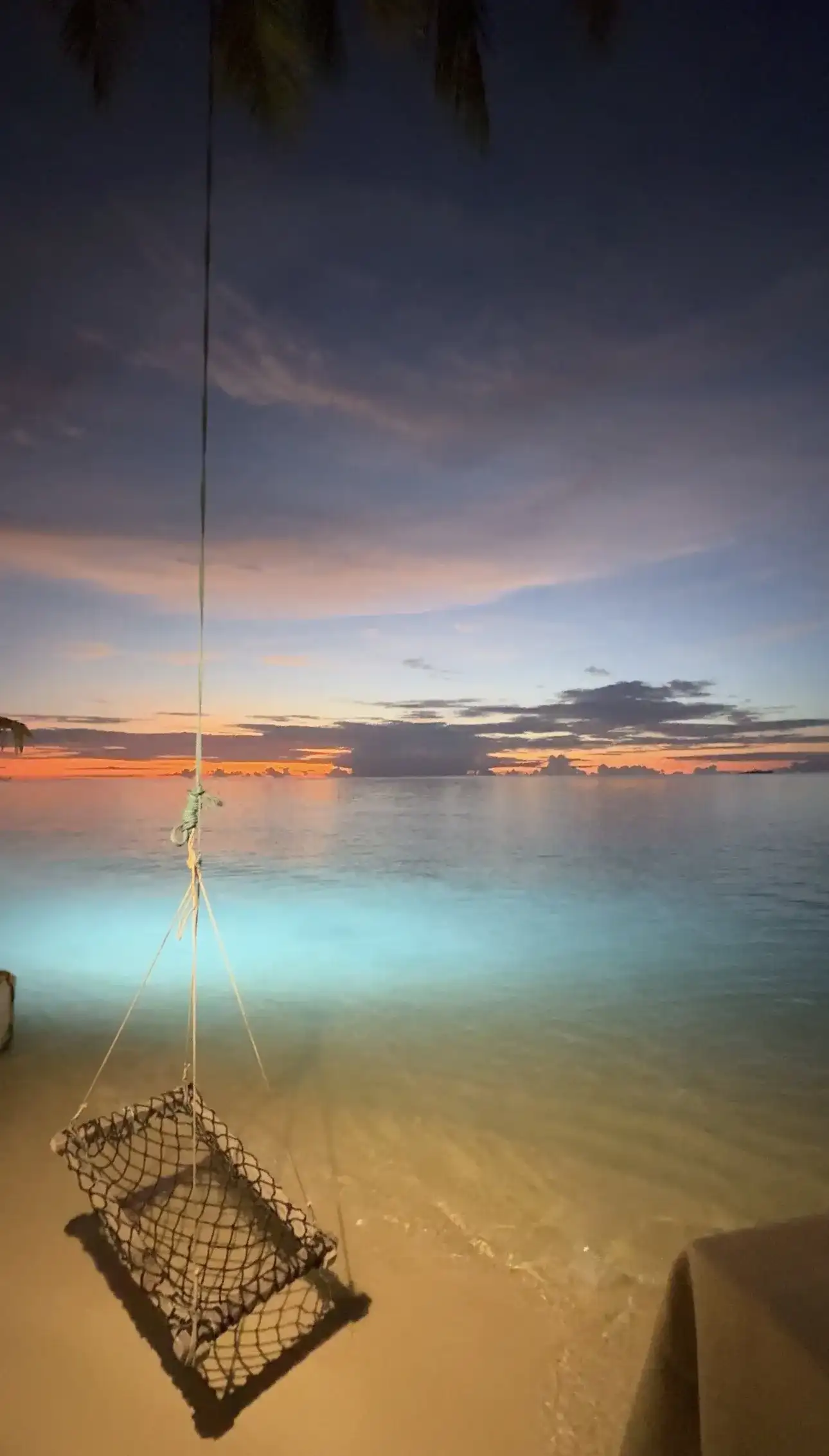 Dusk over the lagoon with a fish trap hanging above lit shallow water