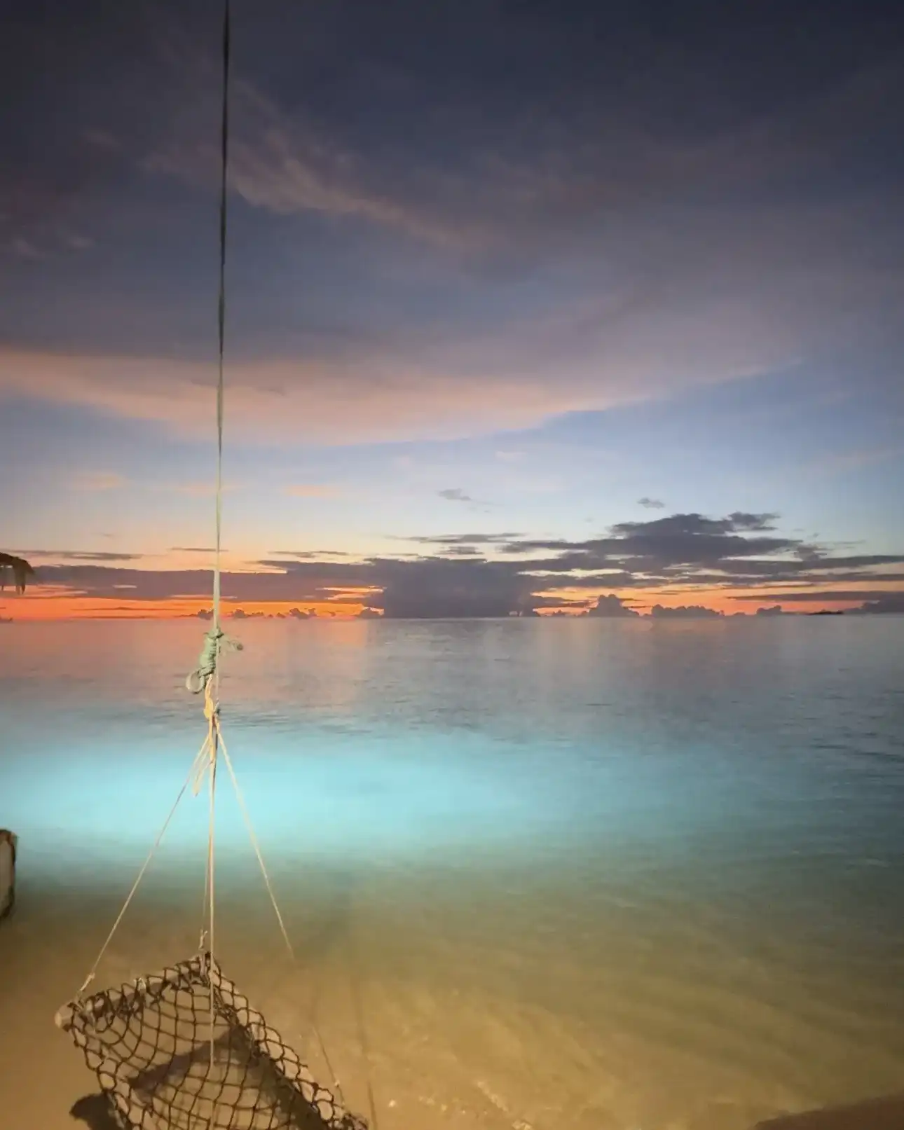 Dusk over the lagoon with a fish trap hanging above lit shallow water