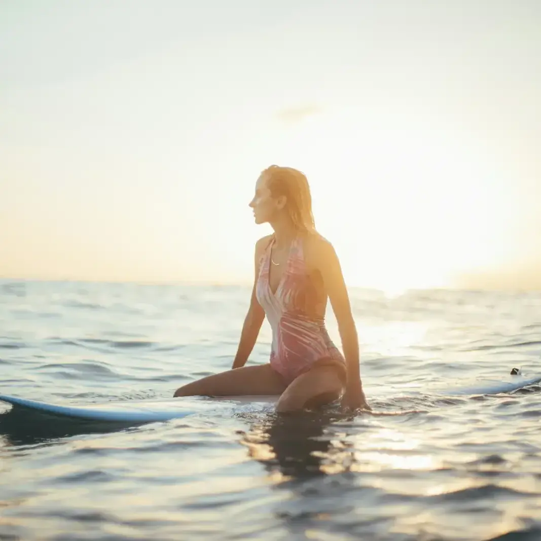 A swimmer standing in calm sea water at sunrise
