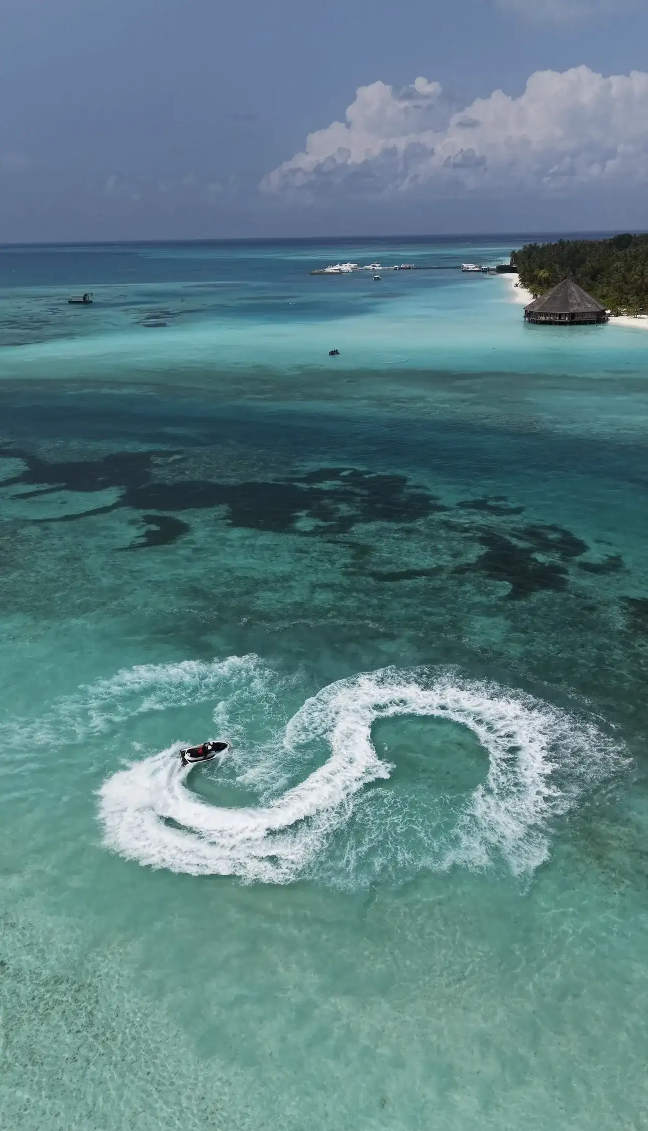 Jet ski carving a figure of eight in a turquoise lagoon near the beach