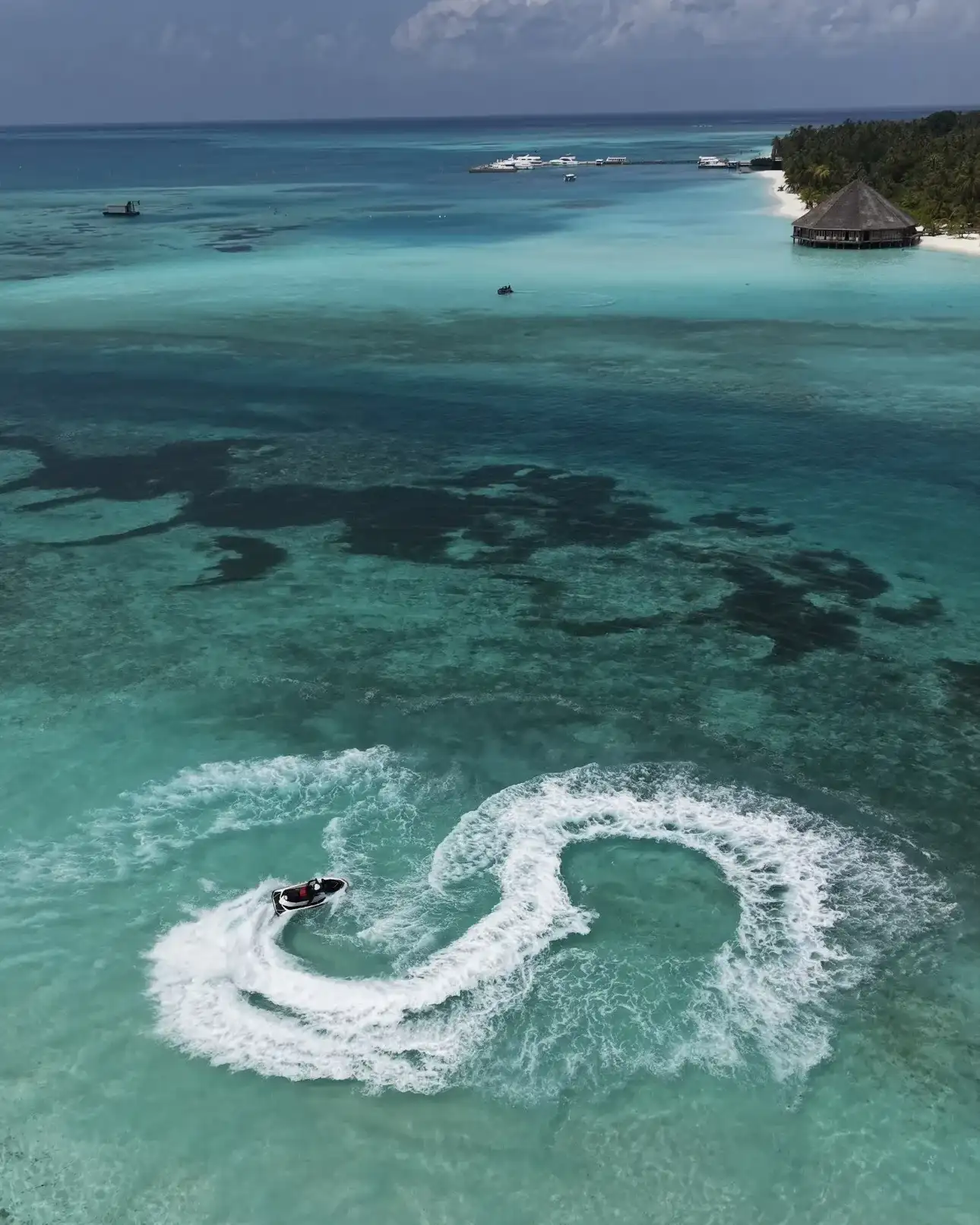 Jet ski carving a figure of eight in a turquoise lagoon near the beach