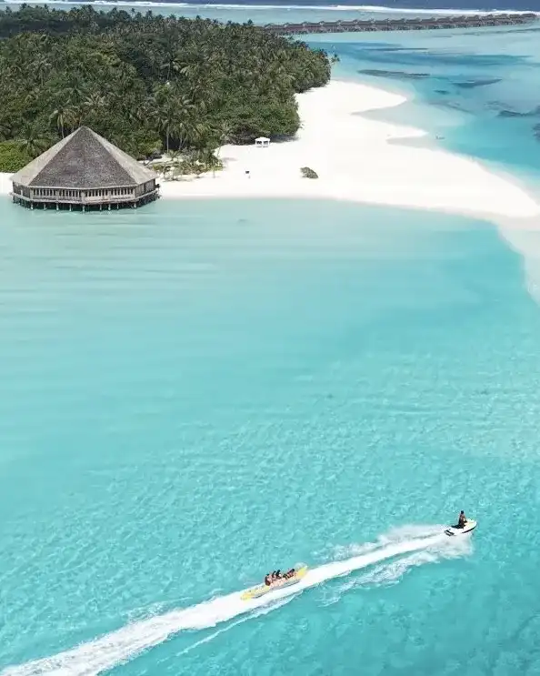 Jet ski crossing a turquoise lagoon past a thatched beach hut