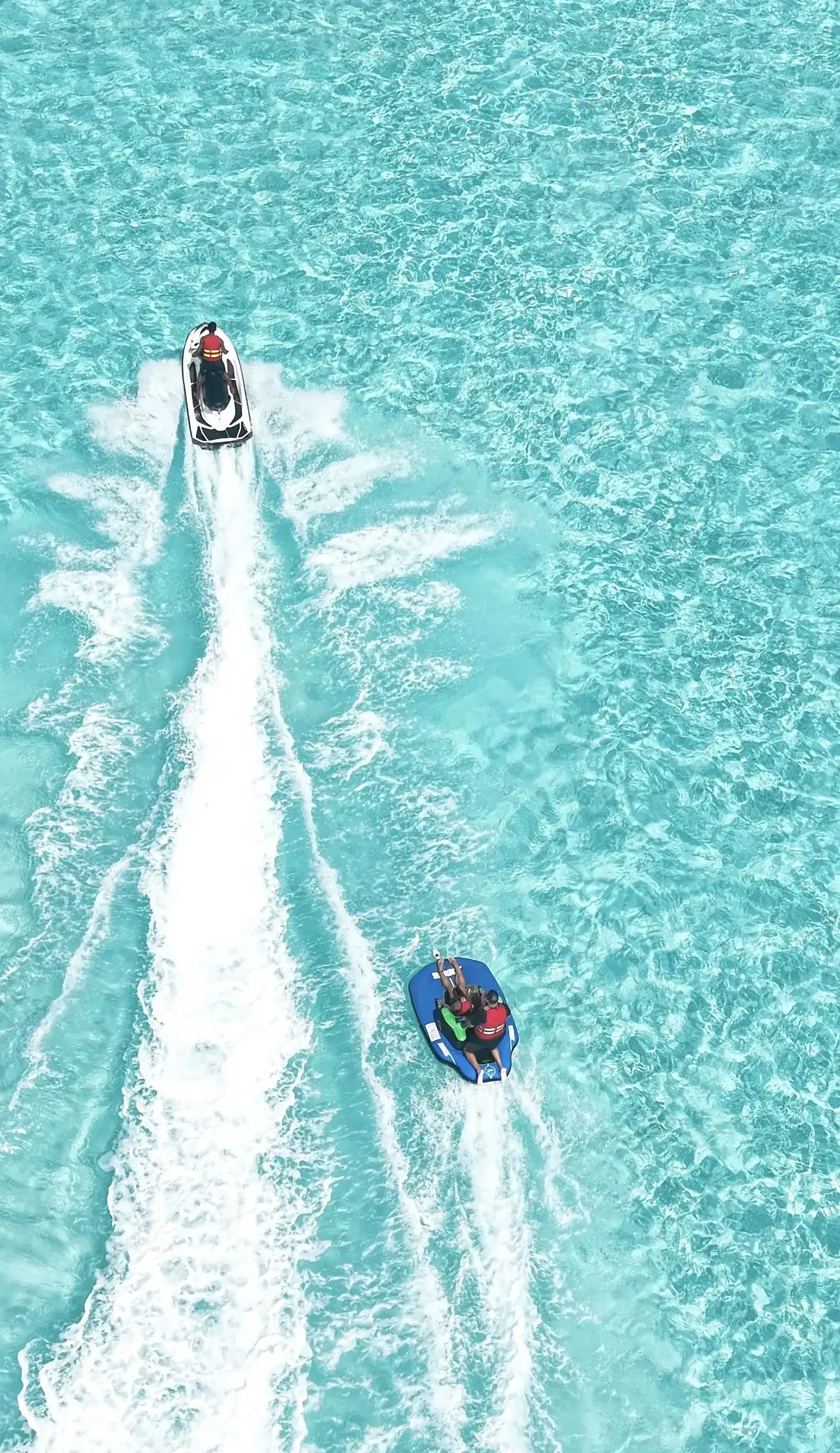 Jet ski towing an inflatable tube ride across a turquoise lagoon
